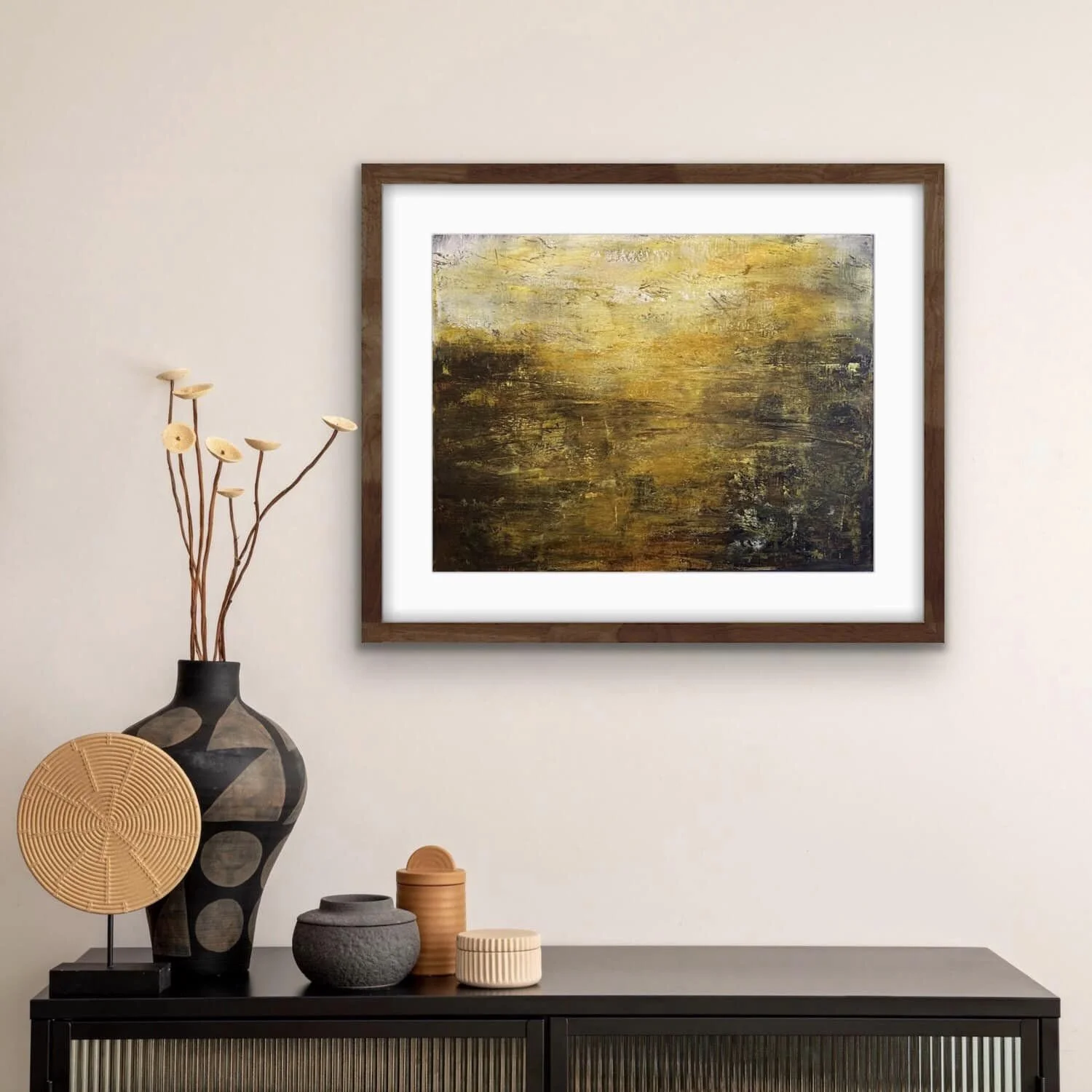 Decorative room with a black sideboard, vase with tall branches and round flower-shaped decorations, abstract painting in a wooden frame on a white wall.