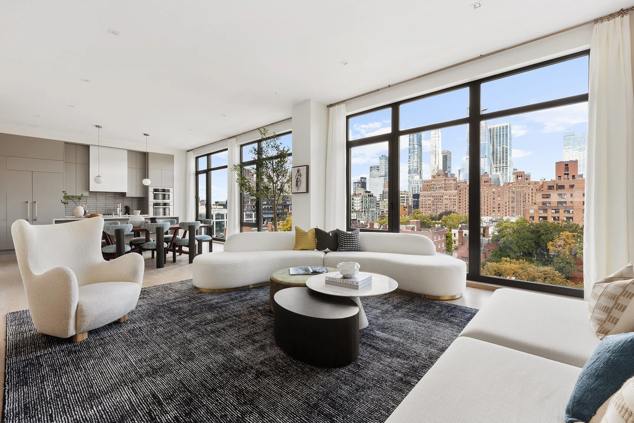 Staging art direction - Modern living room with large floor-to-ceiling windows showcasing a cityscape skyline, white sofas, a round coffee table, and a black-and-white area rug.