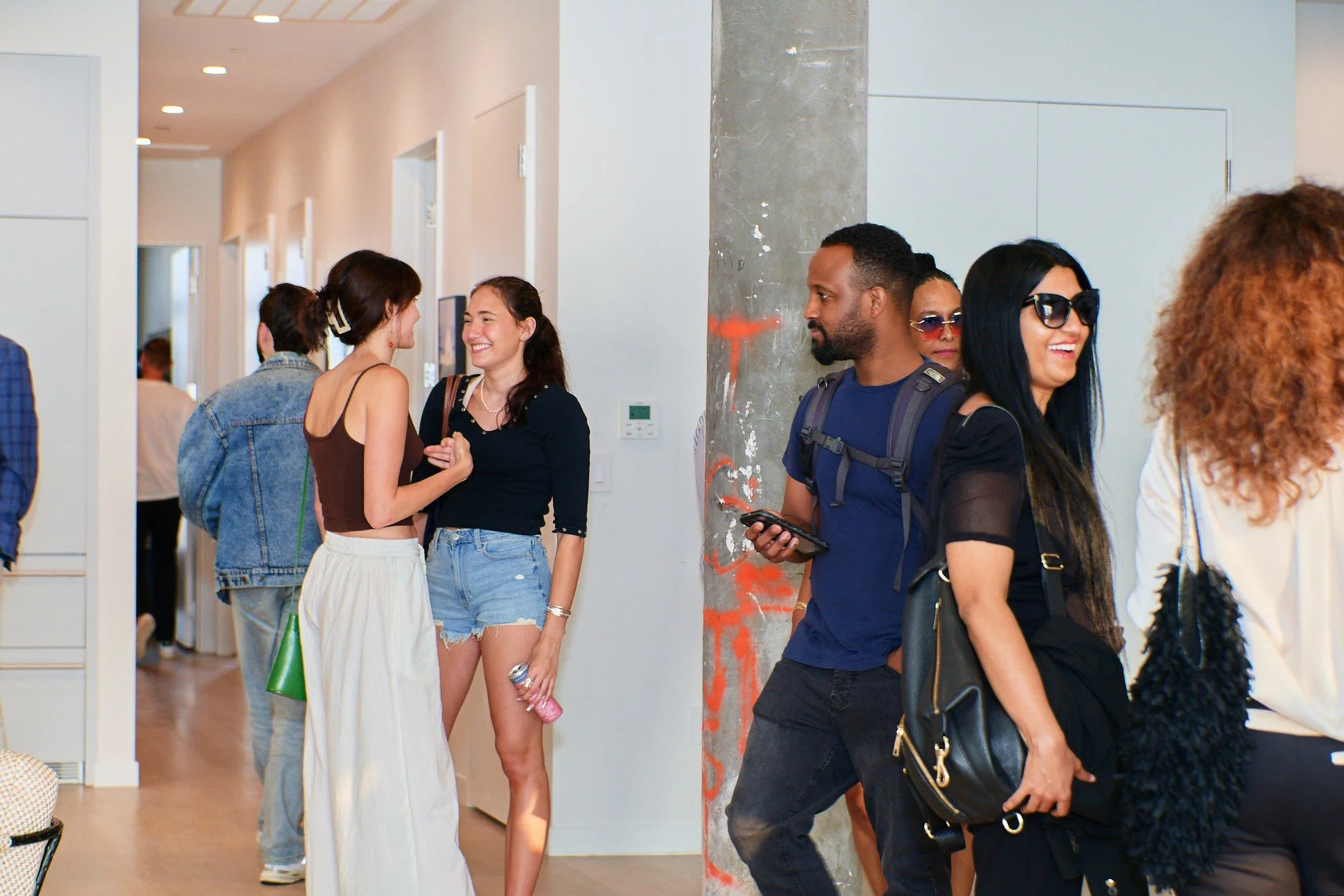 People socializing at a real estate preview event I produced with a concrete pillar and white walls.