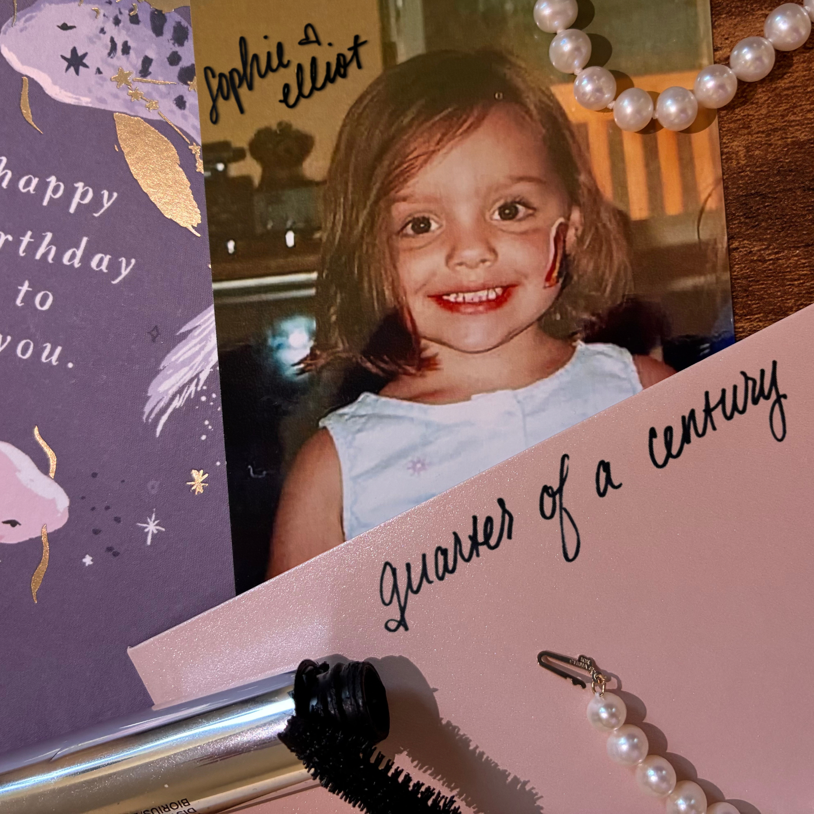 A birthday card with a photo of a smiling young girl with brown hair in pigtails, wearing a white top. It is the cover for Sophie Elliot's debut single "quarter of a century," out on all streaming platforms July 31st. 