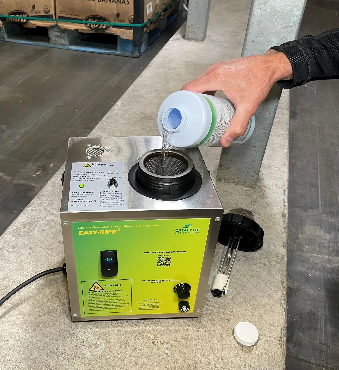 Person pouring Ethy-Gen II into an Easy-Ripe ethylene generator used for fruit ripening in a ripening area.