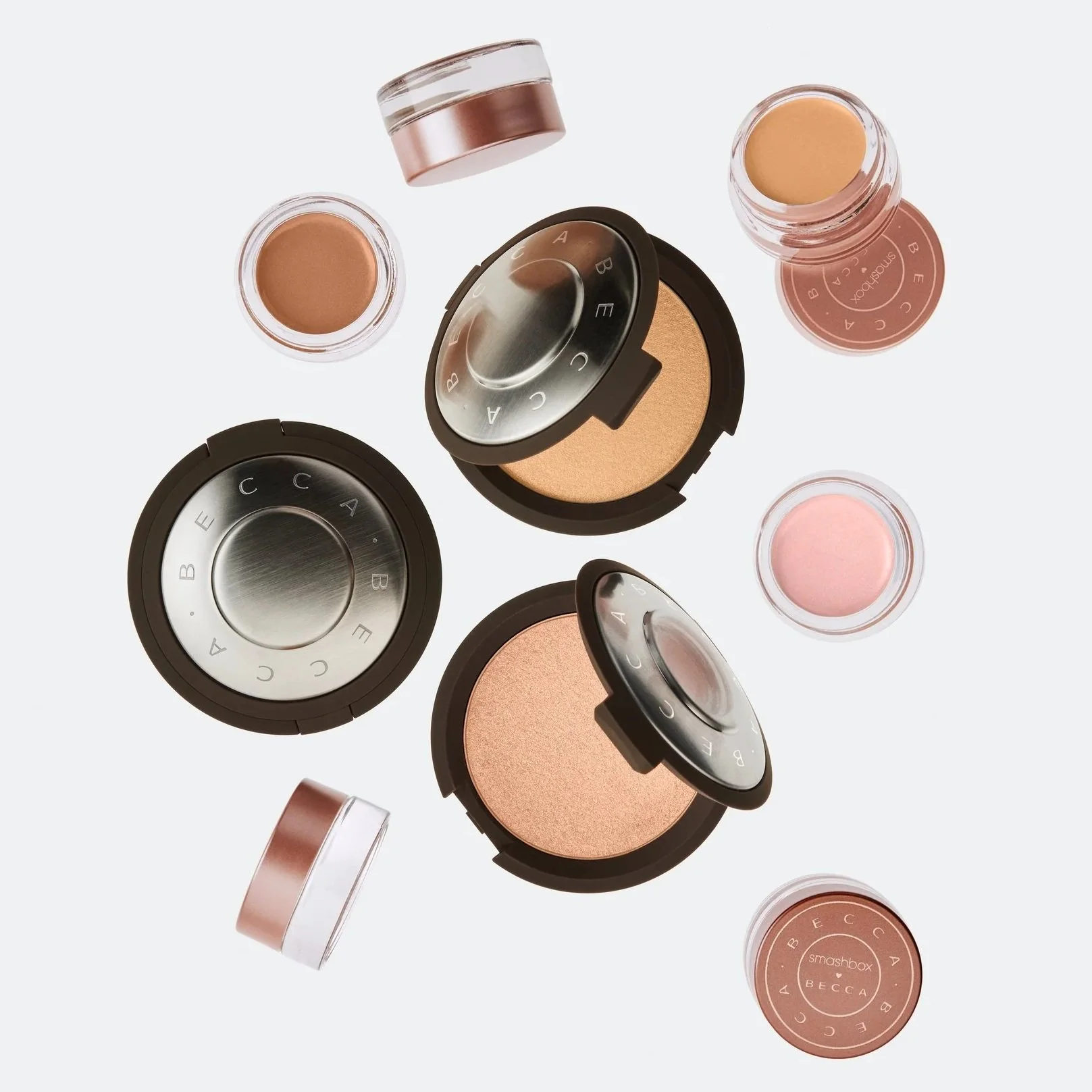 Collection of makeup products including powders and compacts from BECCA, Smashbox, and other brands, arranged on a white background.
