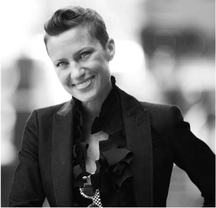Molly Morter, a photo of a smiling woman with short hair, wearing a blazer and a ruffled blouse.