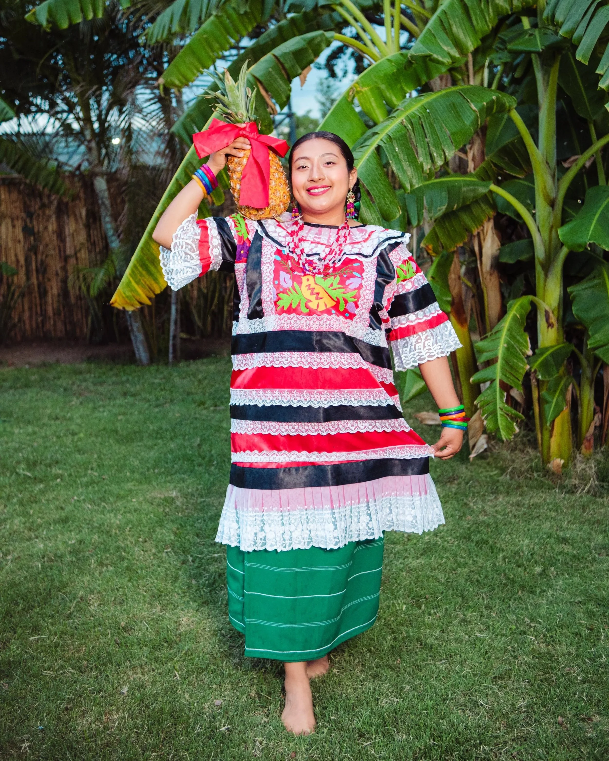 Woman in regional Oaxacan costume carrying a ribboned pineapple, calenda tradition