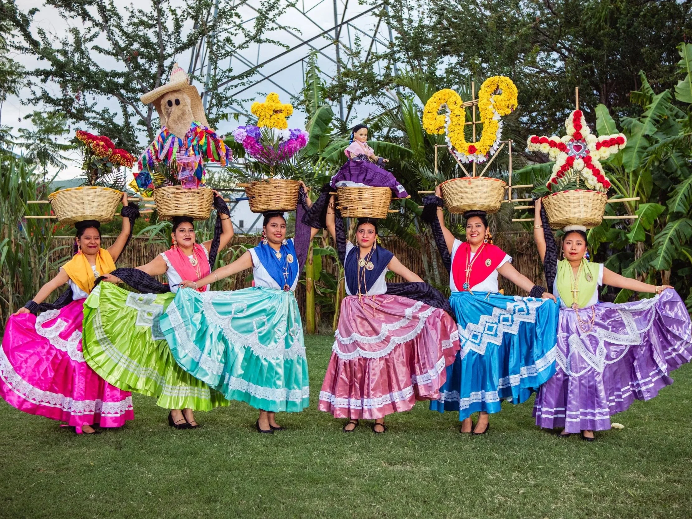Group of Oaxacan dancers carrying floral baskets in a calenda parade