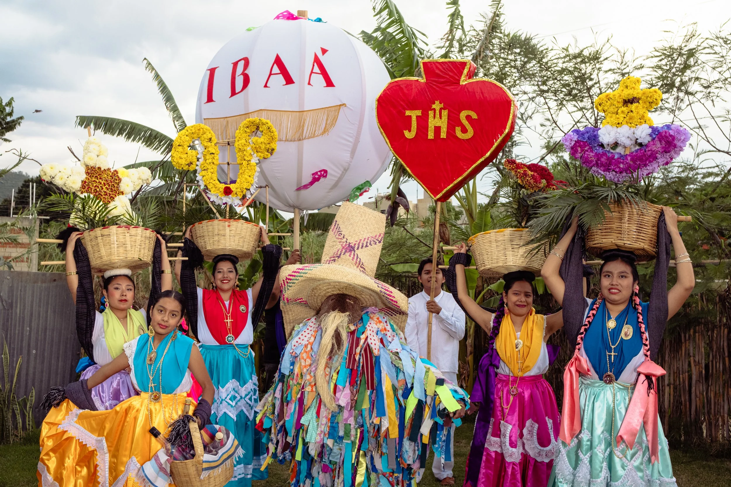 Group of chinas oaxaqueñas, holding baskets on their heads during a cultural parade or festival, in a calenda for a wedding or corporate event