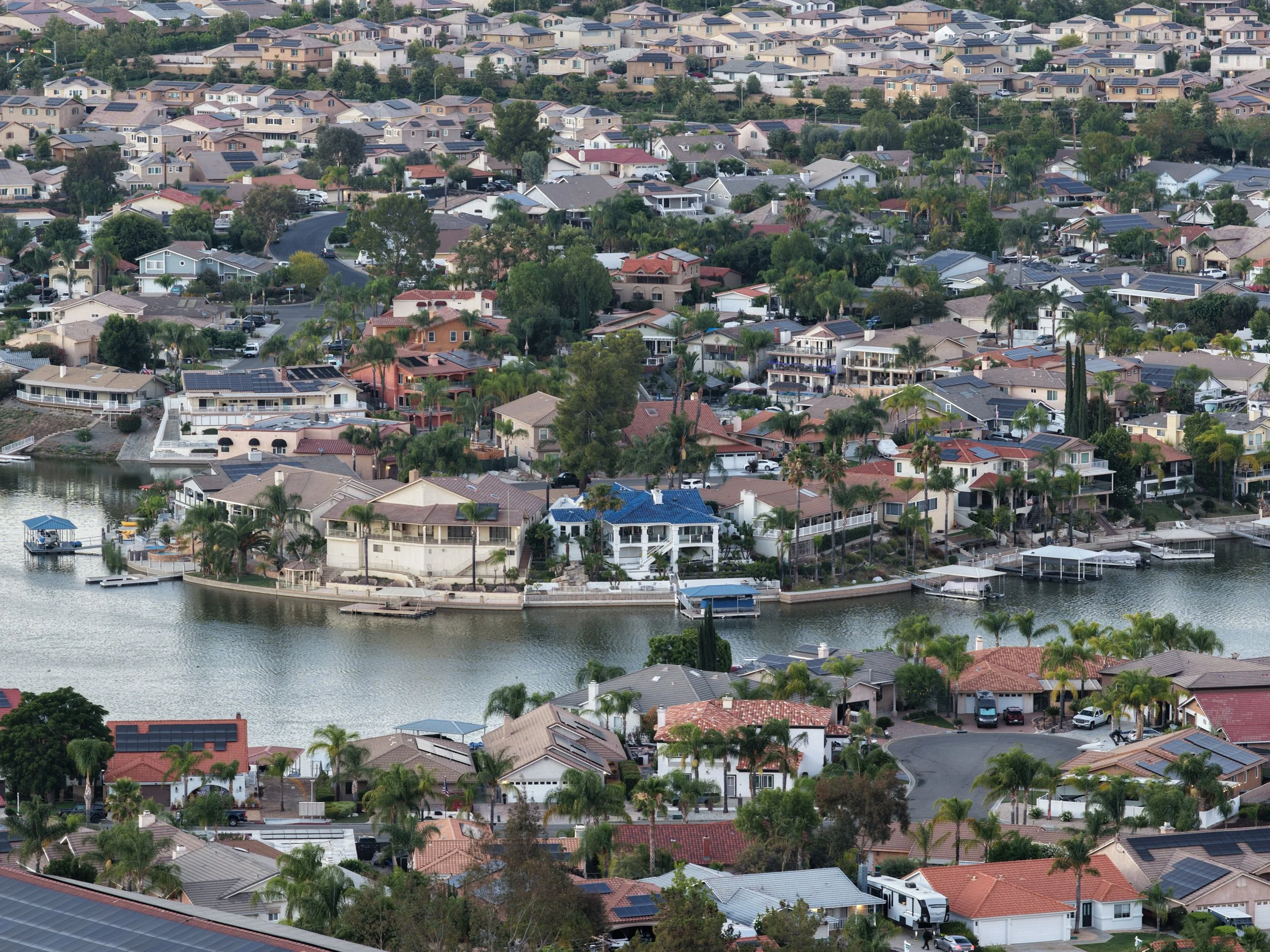 Aerial view of a residential neighborhood with houses, trees, and a waterfront with docks.