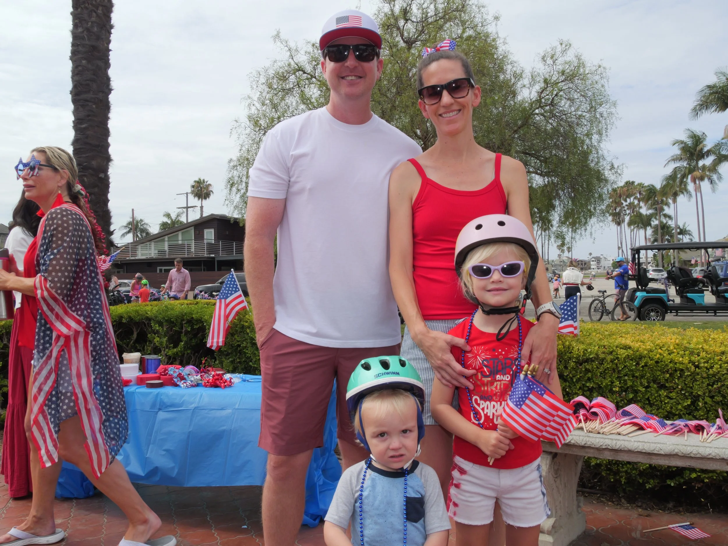 A group of people celebrating on a cloudy day at an outdoor event with American flag decorations, some wearing patriotic clothing and accessories.