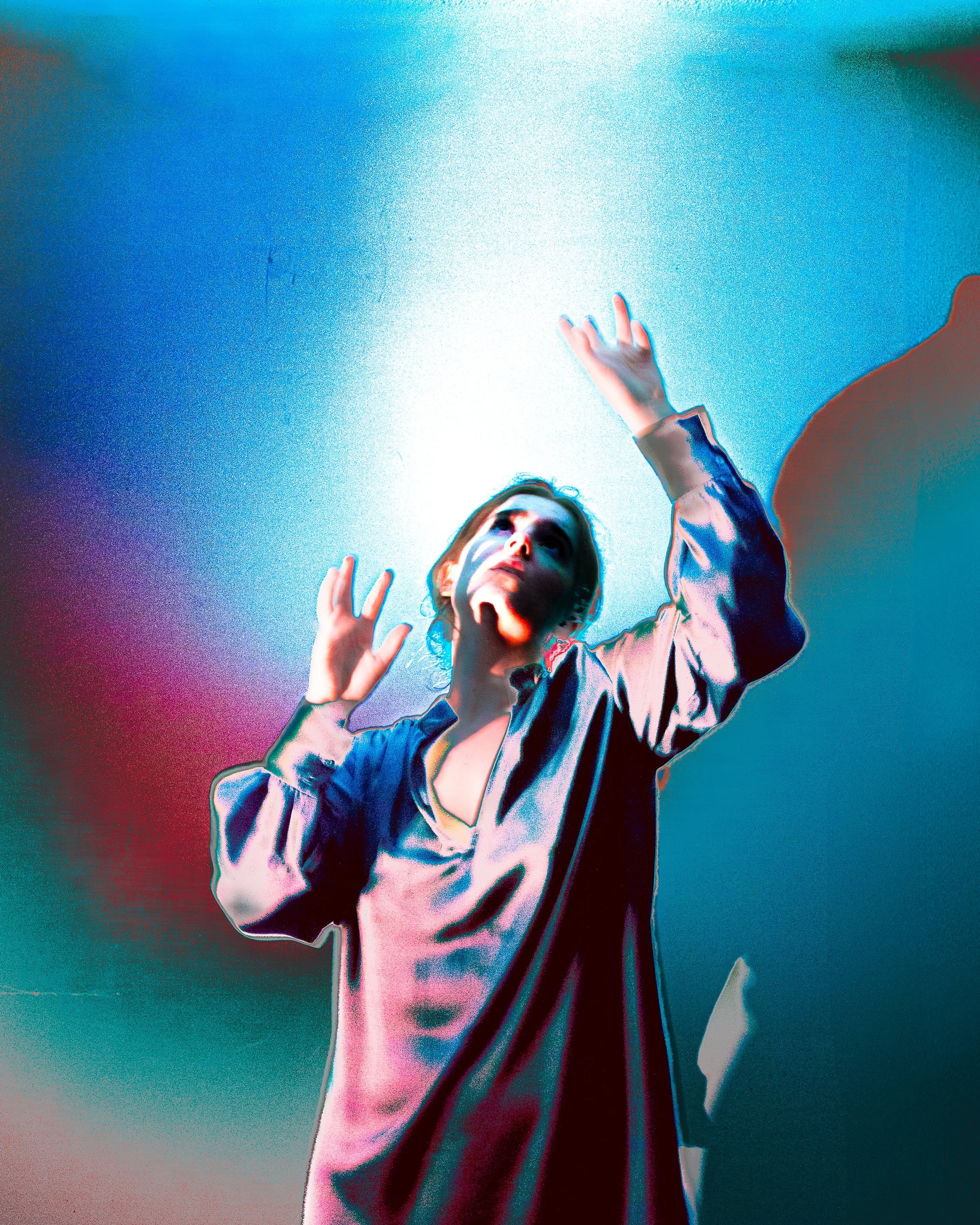 A woman reaching upward with both hands against a colorful, abstract background with shades of blue, pink, and purple.