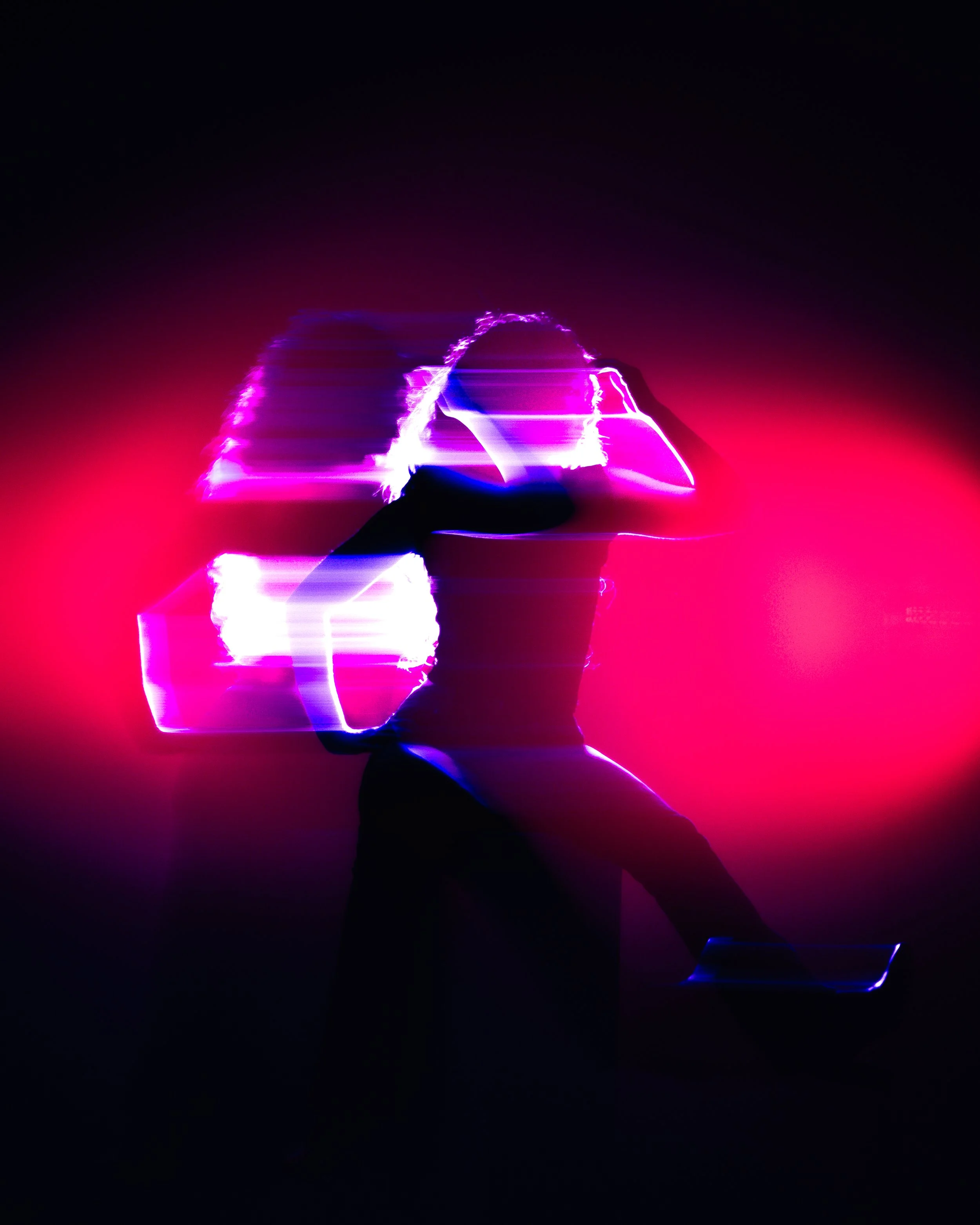 A person holding a tablet or smartphone, with colorful neon light effects creating a silhouette and double exposure effect, in a dark background.