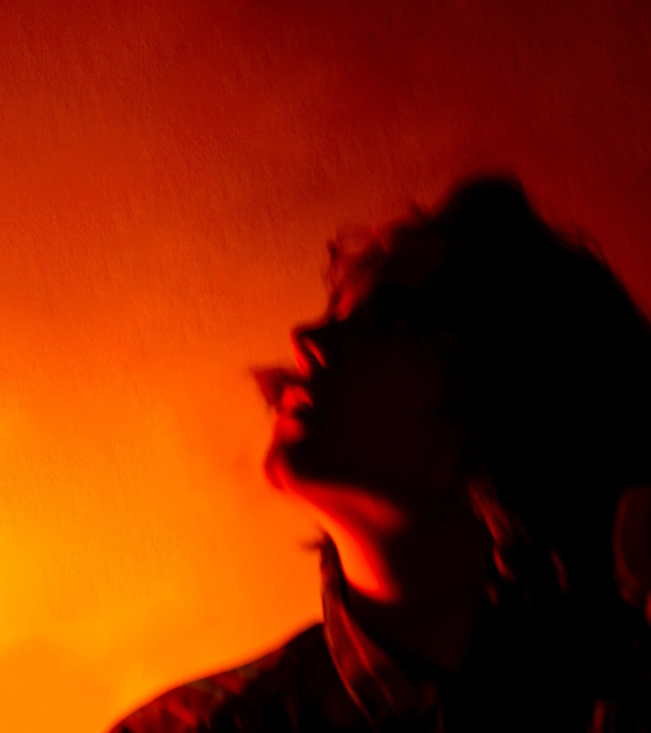 A person's silhouette is visible against a glowing fiery orange and red background, with the person's hair and side profile faintly discernible.