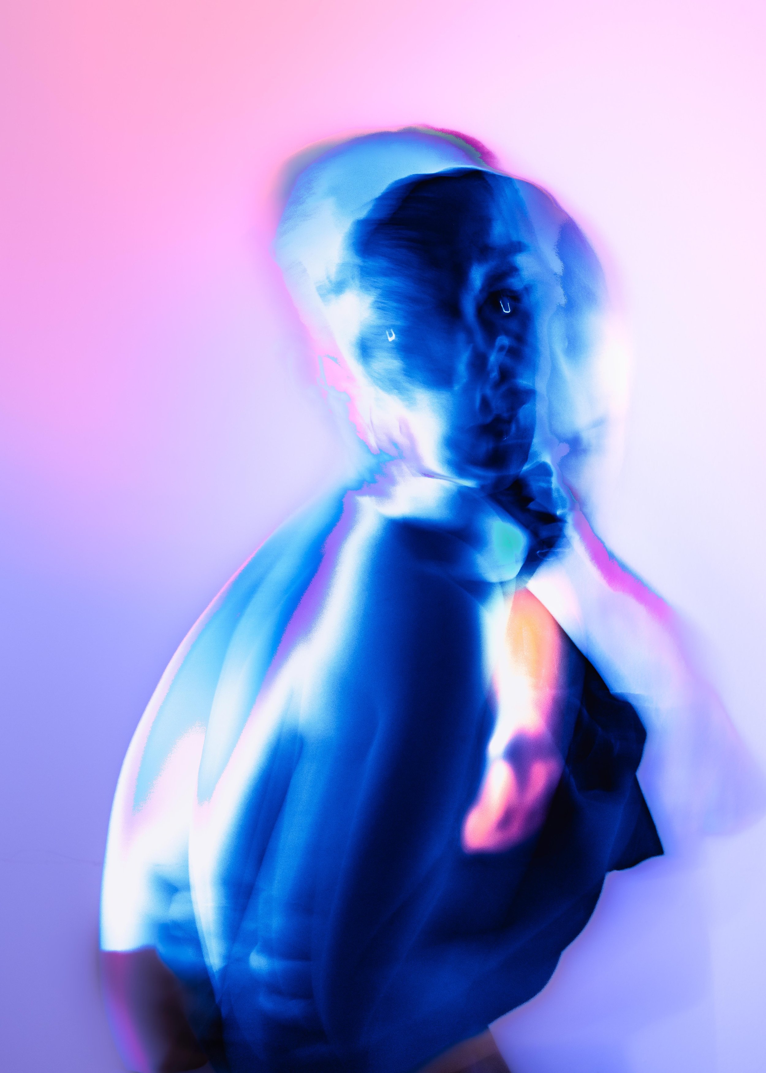 A digitally manipulated image of a woman with short hair and earrings, appearing as a colorful, abstract portrait with glowing, vibrant blue and pink hues.