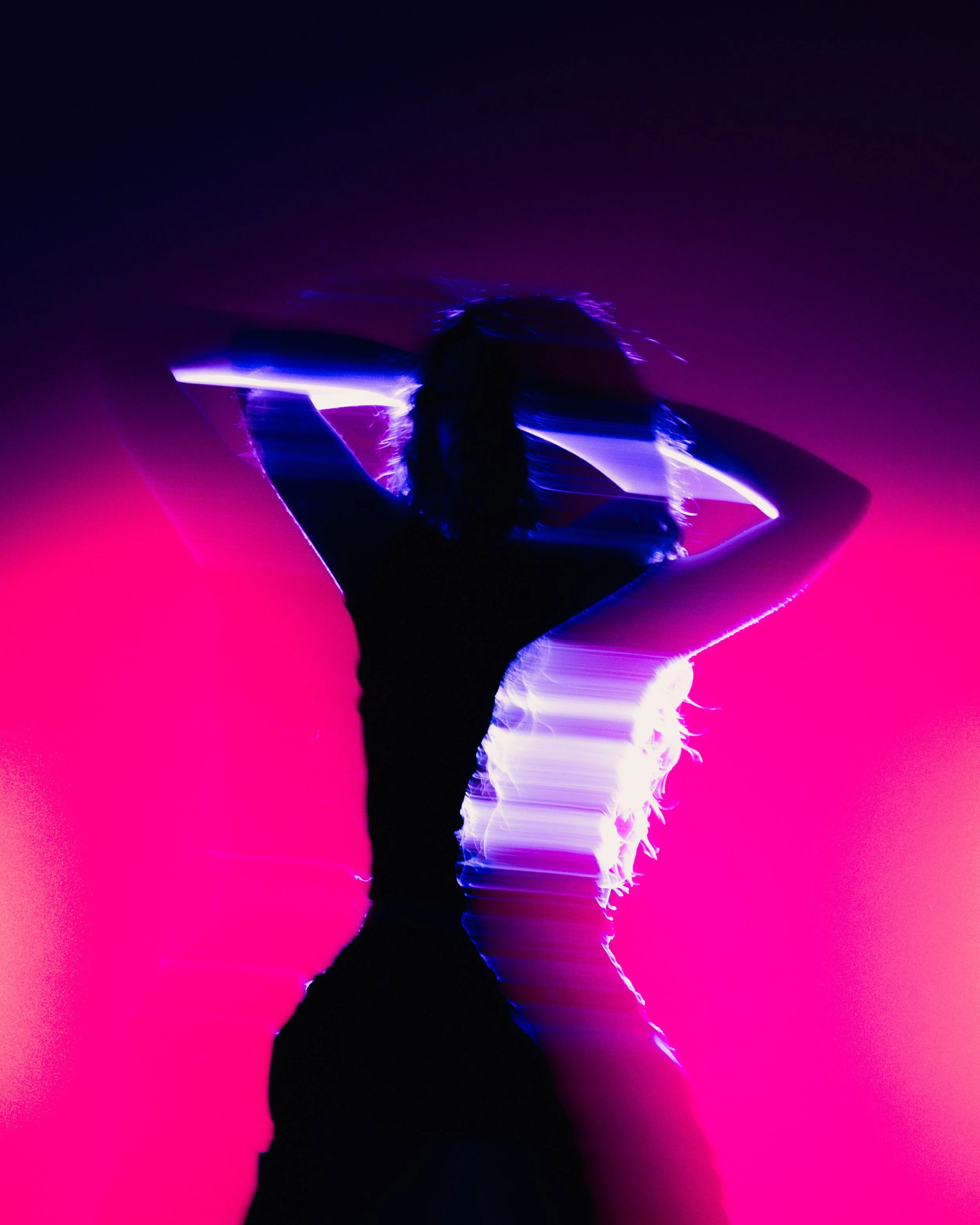 Silhouette of a person with arms raised, surrounded by vibrant purple, blue, and pink neon lights creating a dynamic, abstract glow effect.