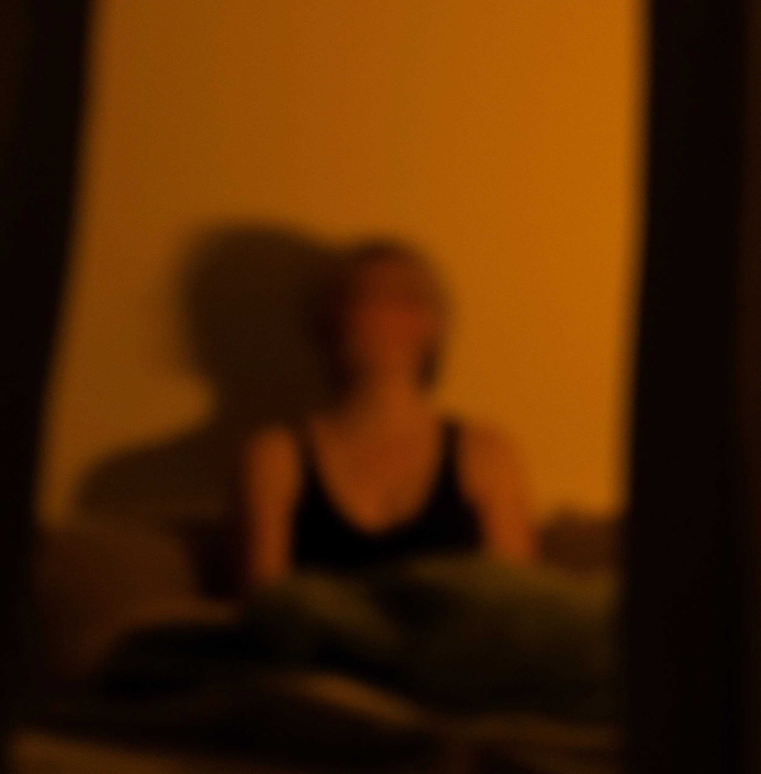 Blurred image with warm colors, primarily orange, with some dark areas.