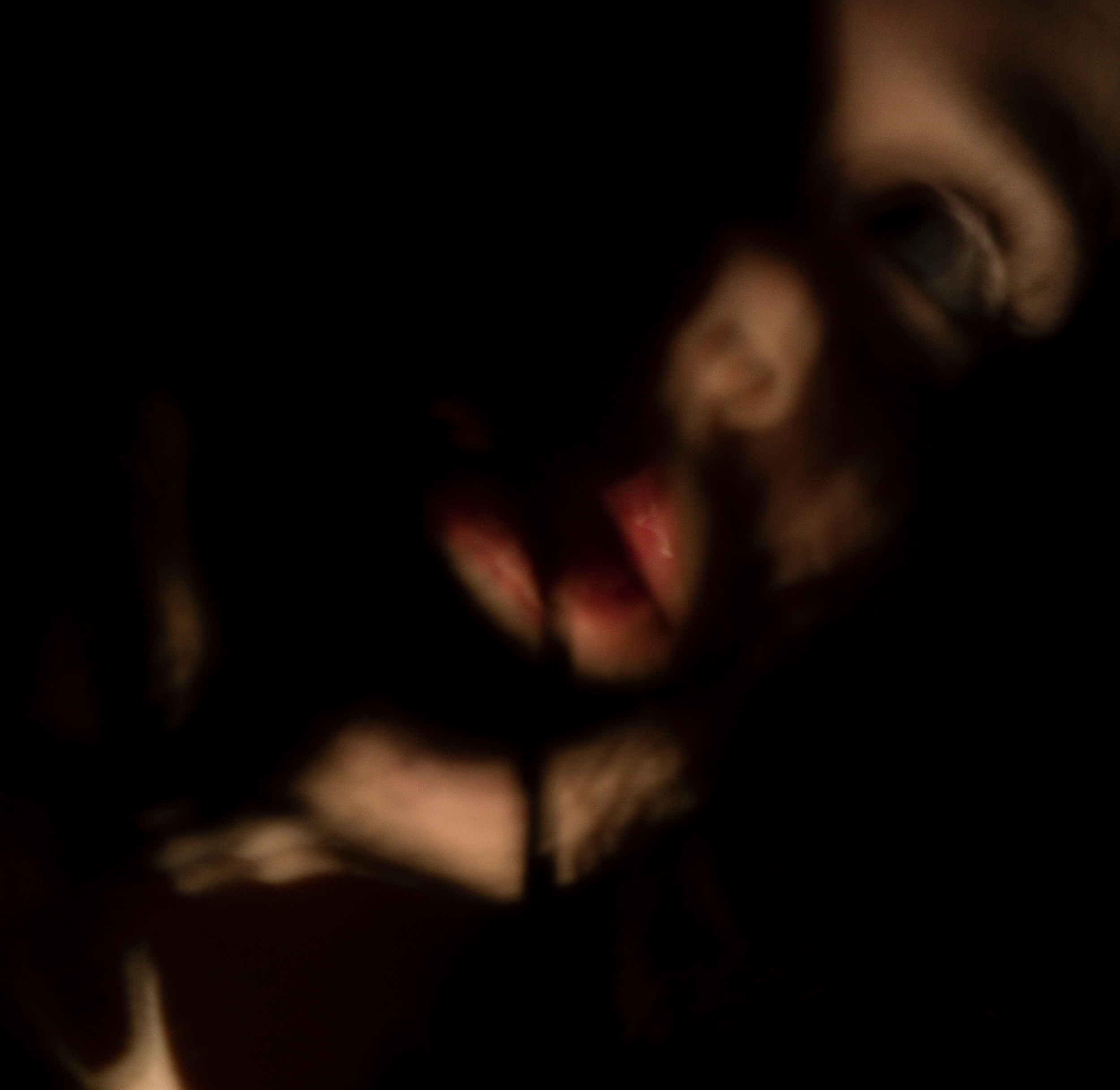 Close-up of a person’s eye, with blurred facial features in a dark environment.