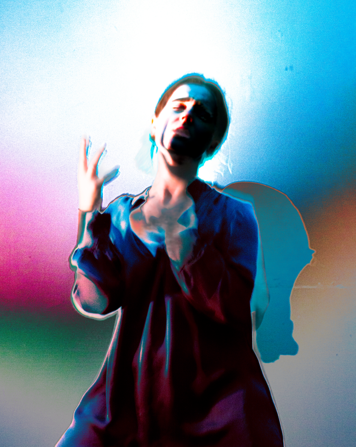 A woman with short hair appears distressed or crying, with colorful digital distortion effects and a gradient background.