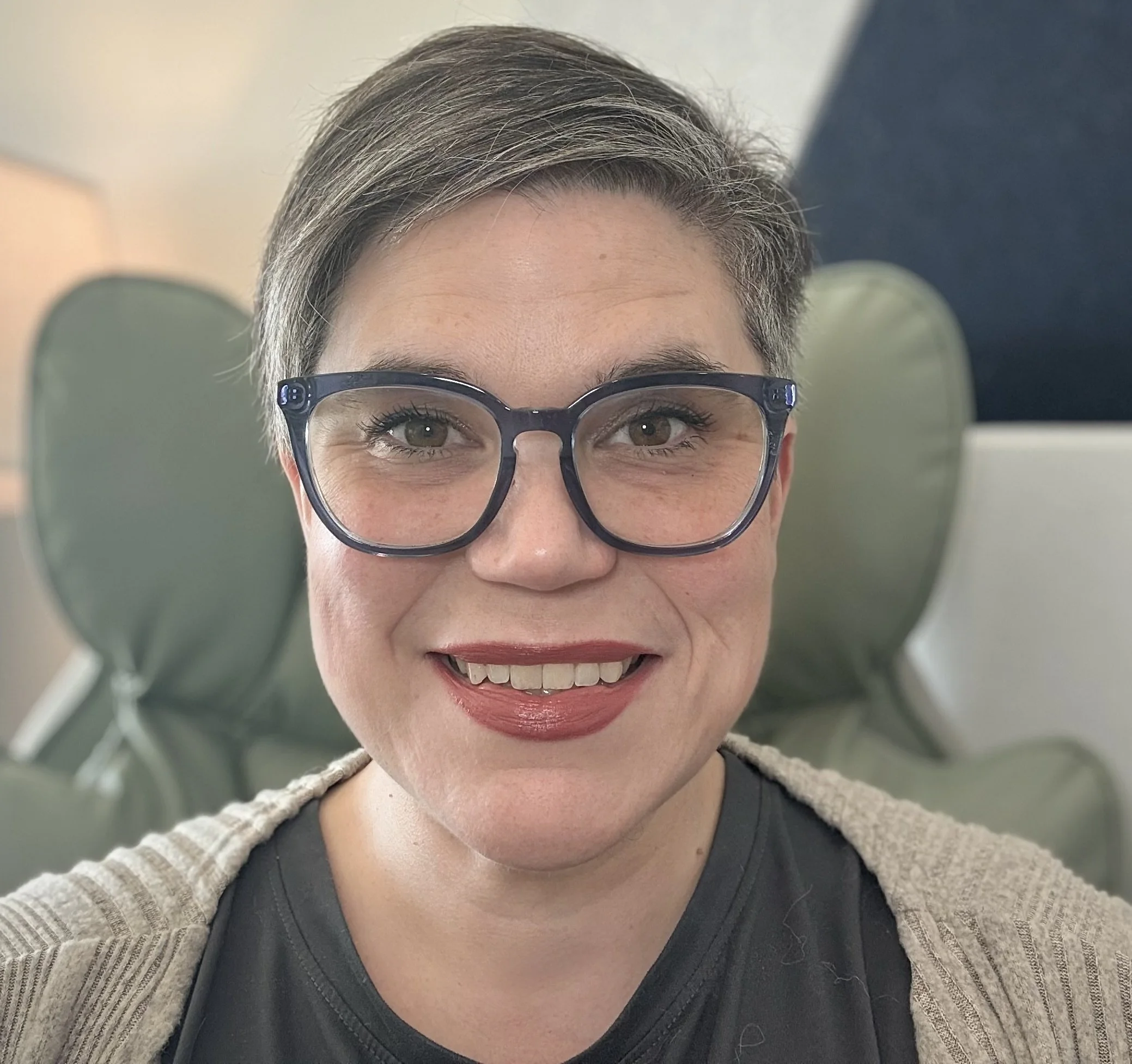 A woman, Dr. Stacy Andrews, looks at the camera. She is wearing thick-rimmed glasses and is smiling.