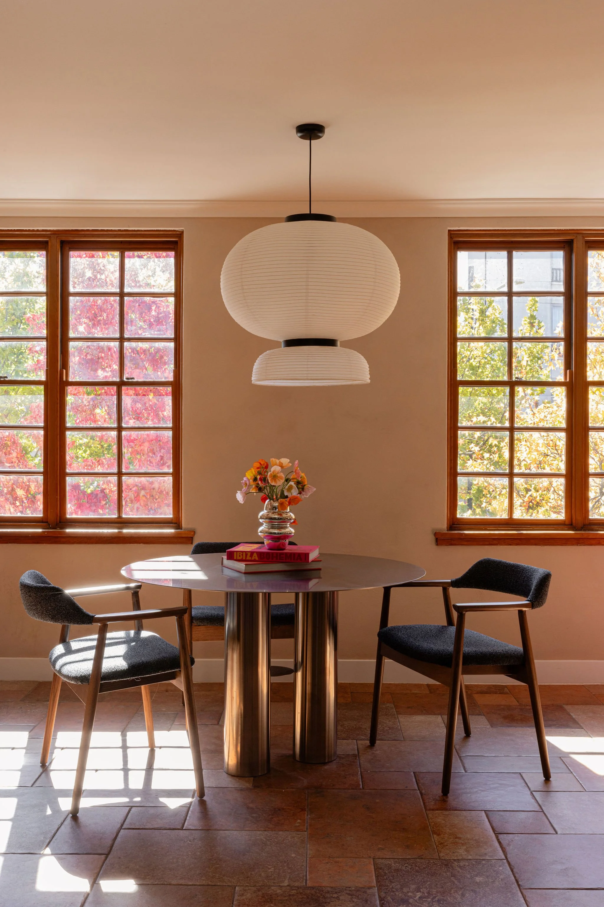 Light-filled salon space with a round timber, pendant light and views of autumn foliage.