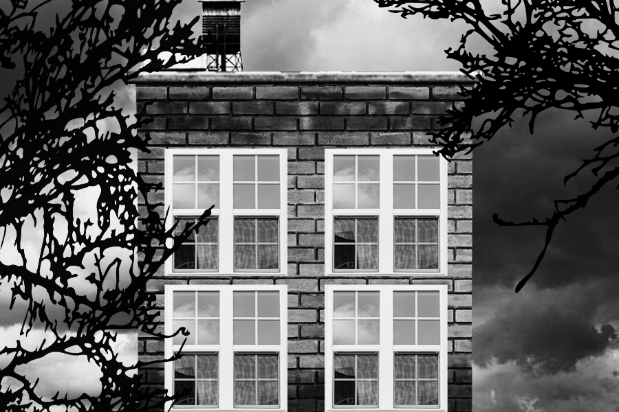 Black and white photo of a brick apartment building with four windows, silhouetted tree branches at the edges, and dark cloudy sky in the background.