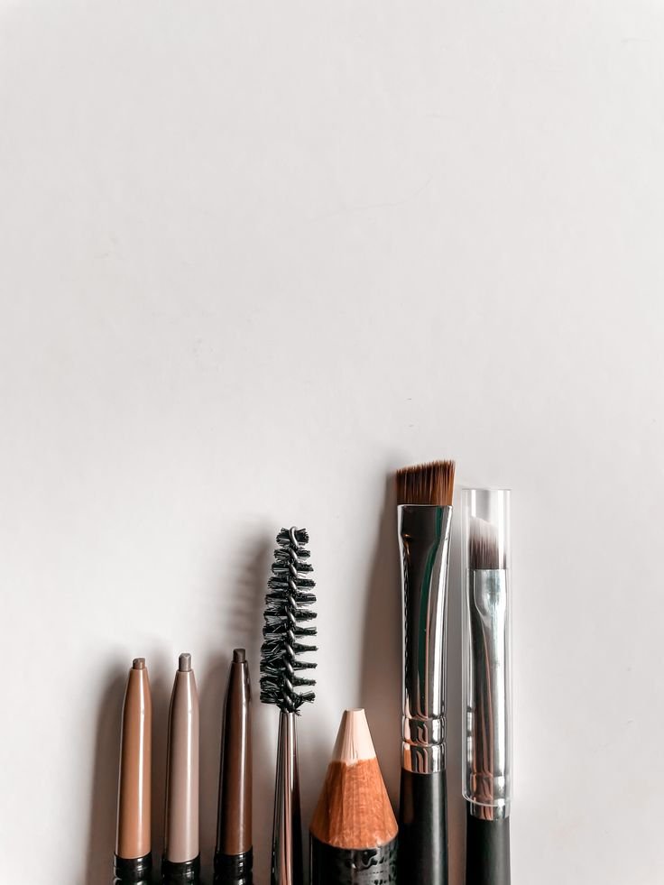 A collection of makeup brushes and applicators arranged vertically on a white surface.