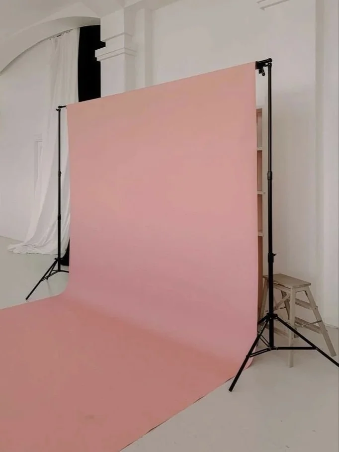 Photography backdrop stand with a pink backdrop in a studio setting.