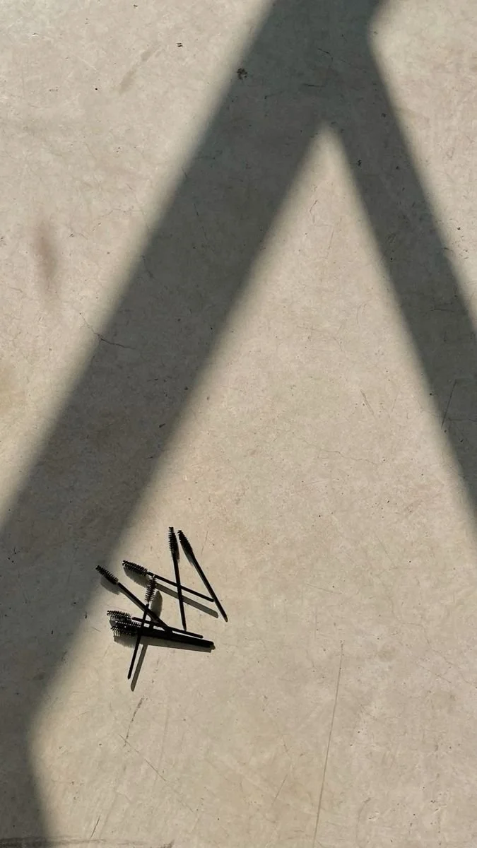 Shadow of a ladder on a concrete floor with a small pile of hair clips and hairpins in the foreground, gives off a editorial vibe.