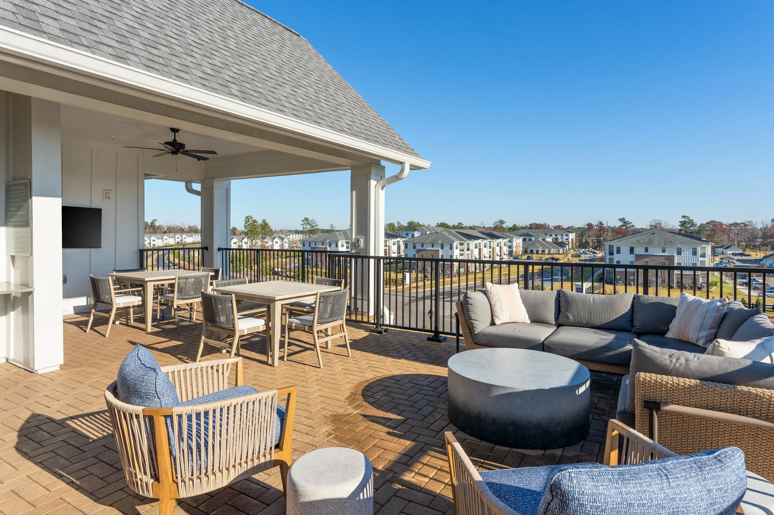 Oak Grove at Blake Farm An outdoor rooftop patio with a seating area including a sectional sofa, chairs, and tables.