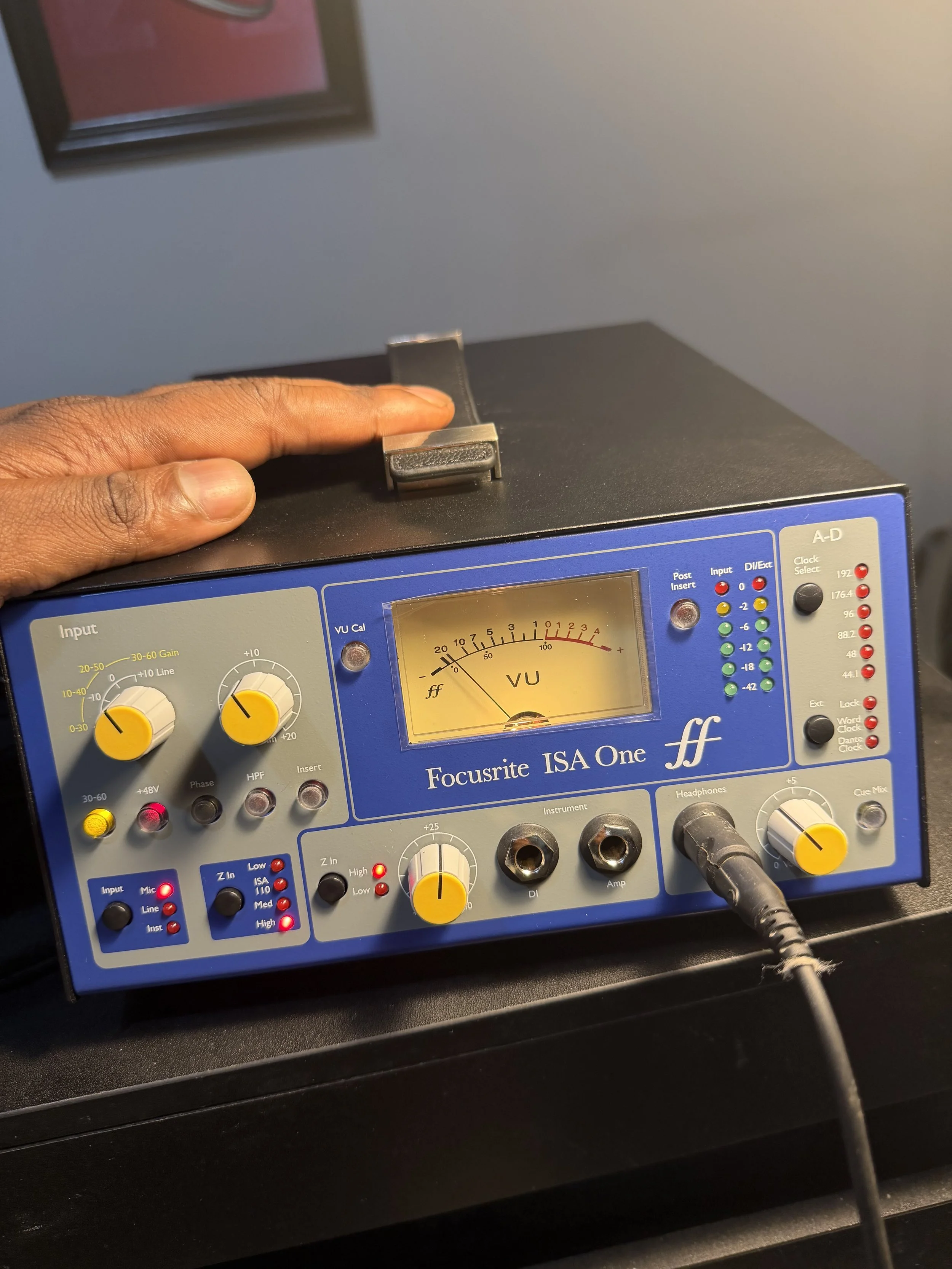 Close-up of a Focusrite ISA One audio interface with a person's hand adjusting a knob on the top.