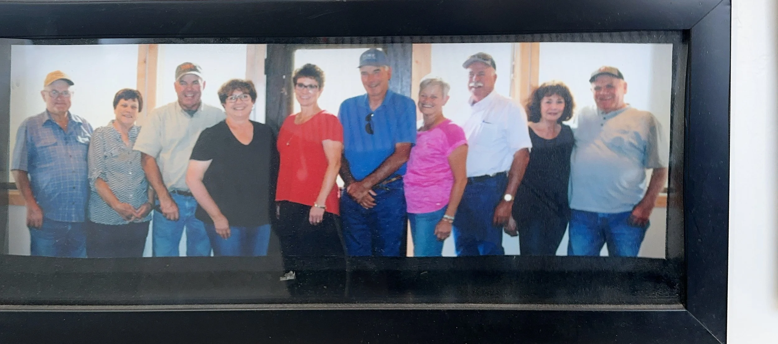 Group of ten people standing indoors, smiling for the camera, with wooden beams visible in the background.