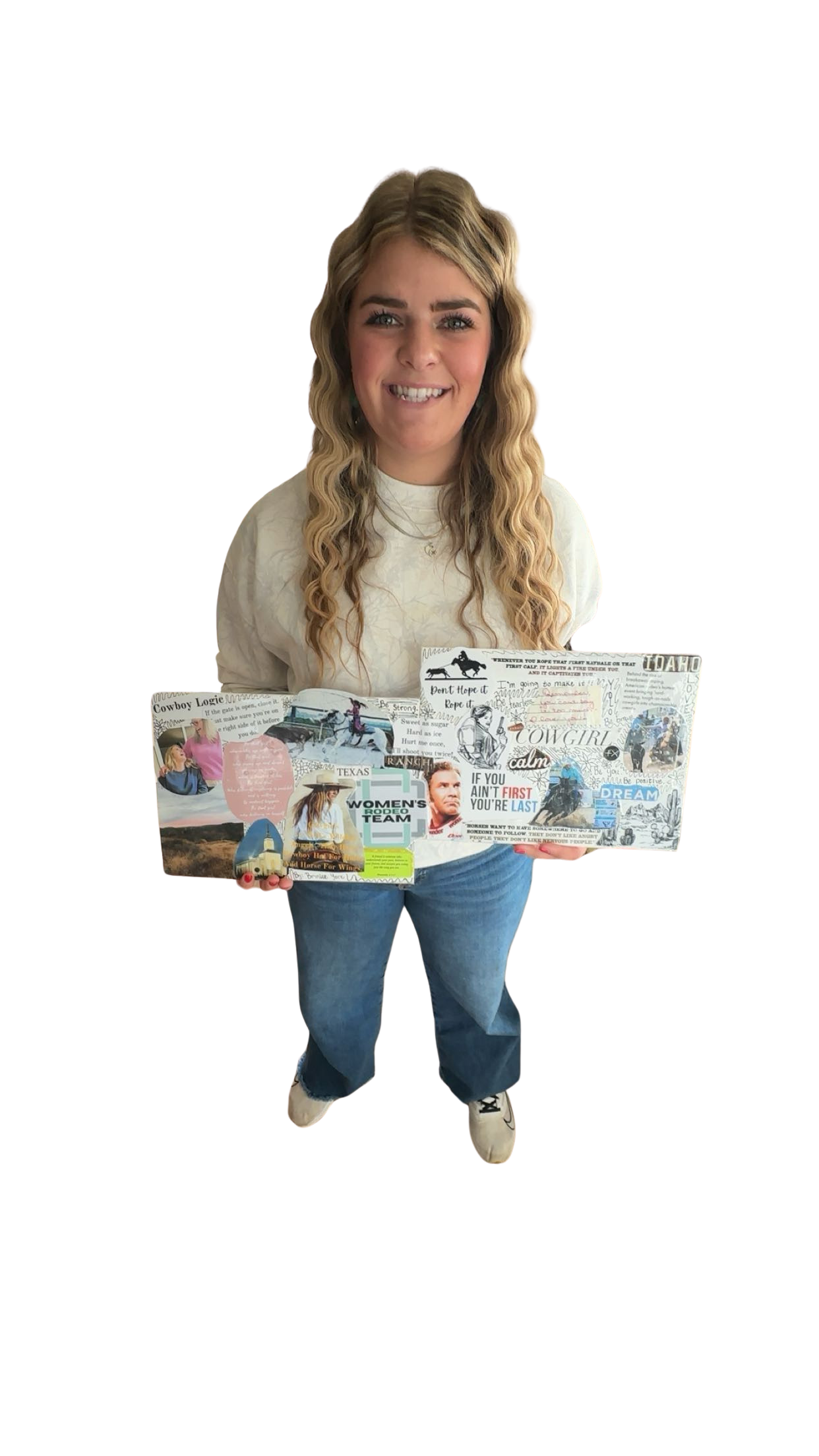 Young woman with wavy blonde hair smiling, holding a decorated poster board with various images and text, dressed in a white sweatshirt and jeans, standing against a black background.