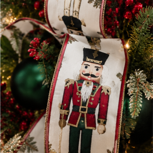 Decorative Christmas ribbon with a Nutcracker soldier design hanging on a Christmas tree with ornaments and pine branches.