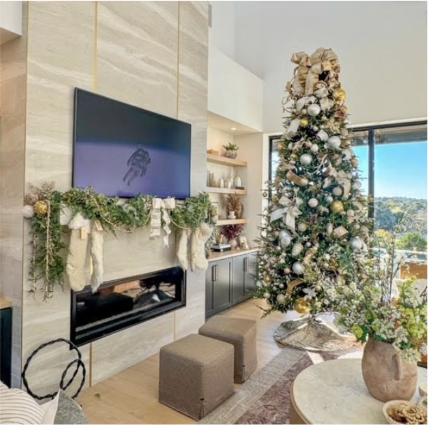 Decorated Christmas tree next to a modern fireplace with holiday garland, stockings, and a TV, in a cozy living room.