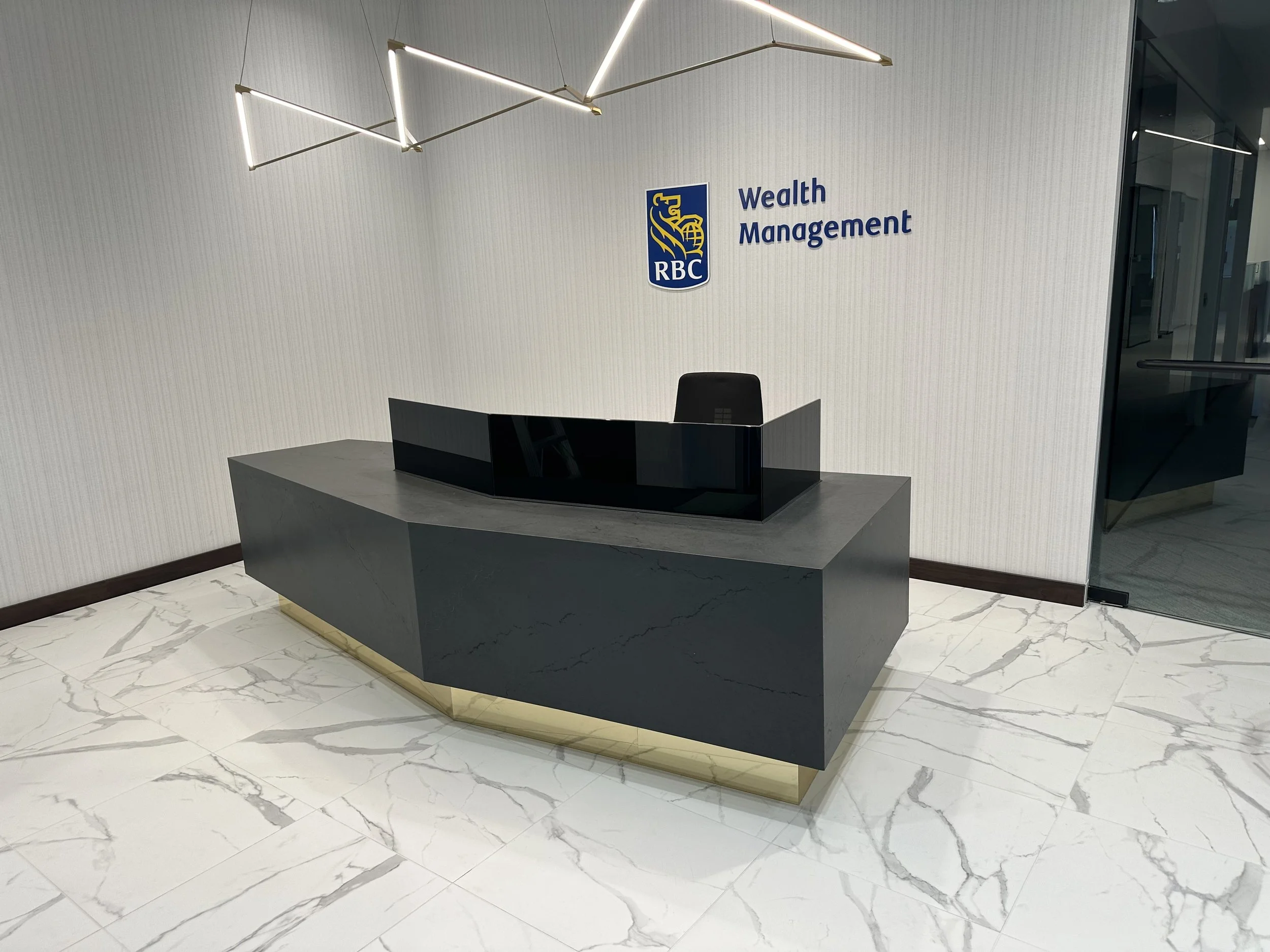 Modern commercial reception desk with a dark stone countertop installed in Houston, TX.
