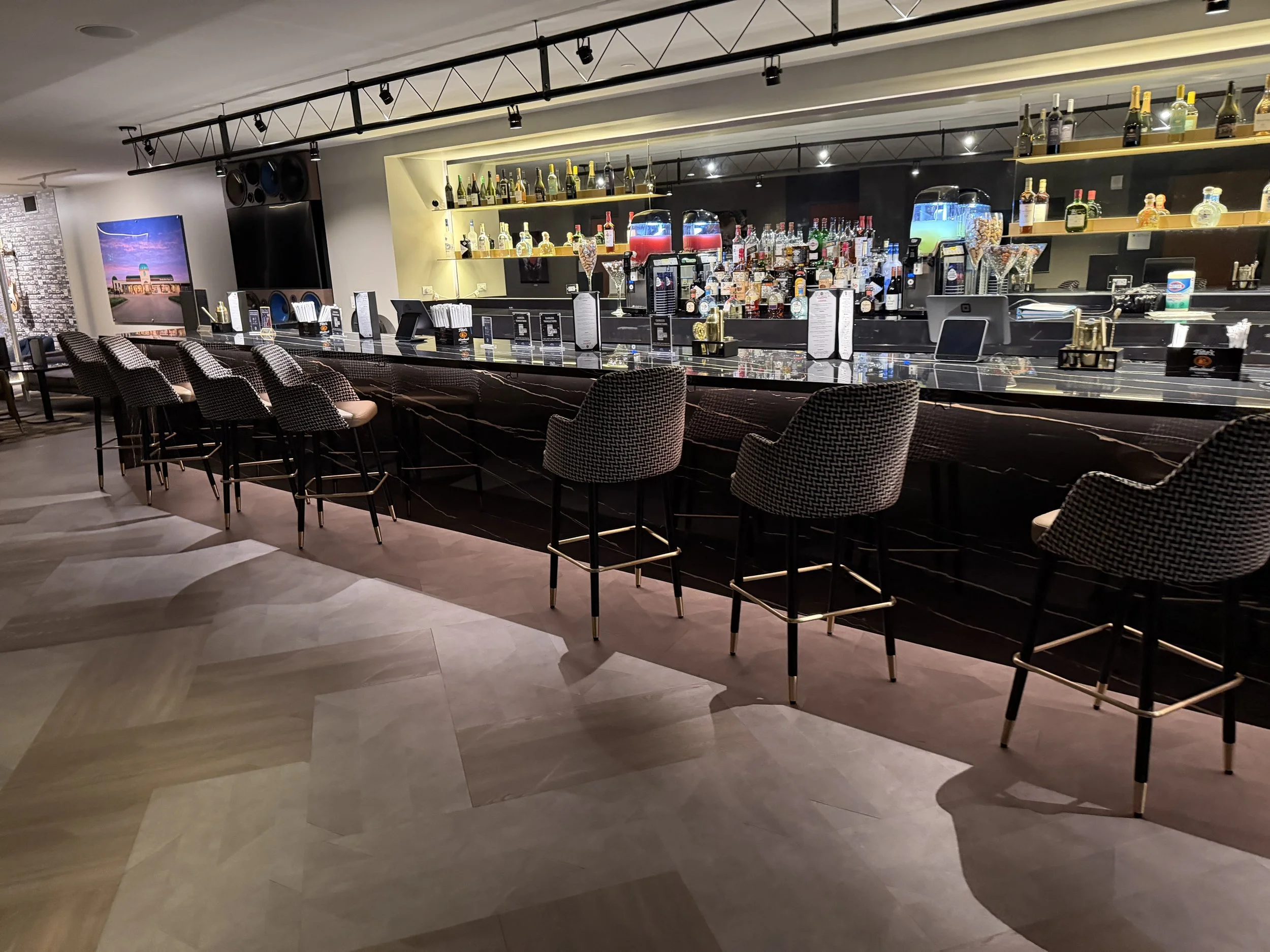 Custom commercial bar with a dark stone countertop and modern seating in Houston, TX.