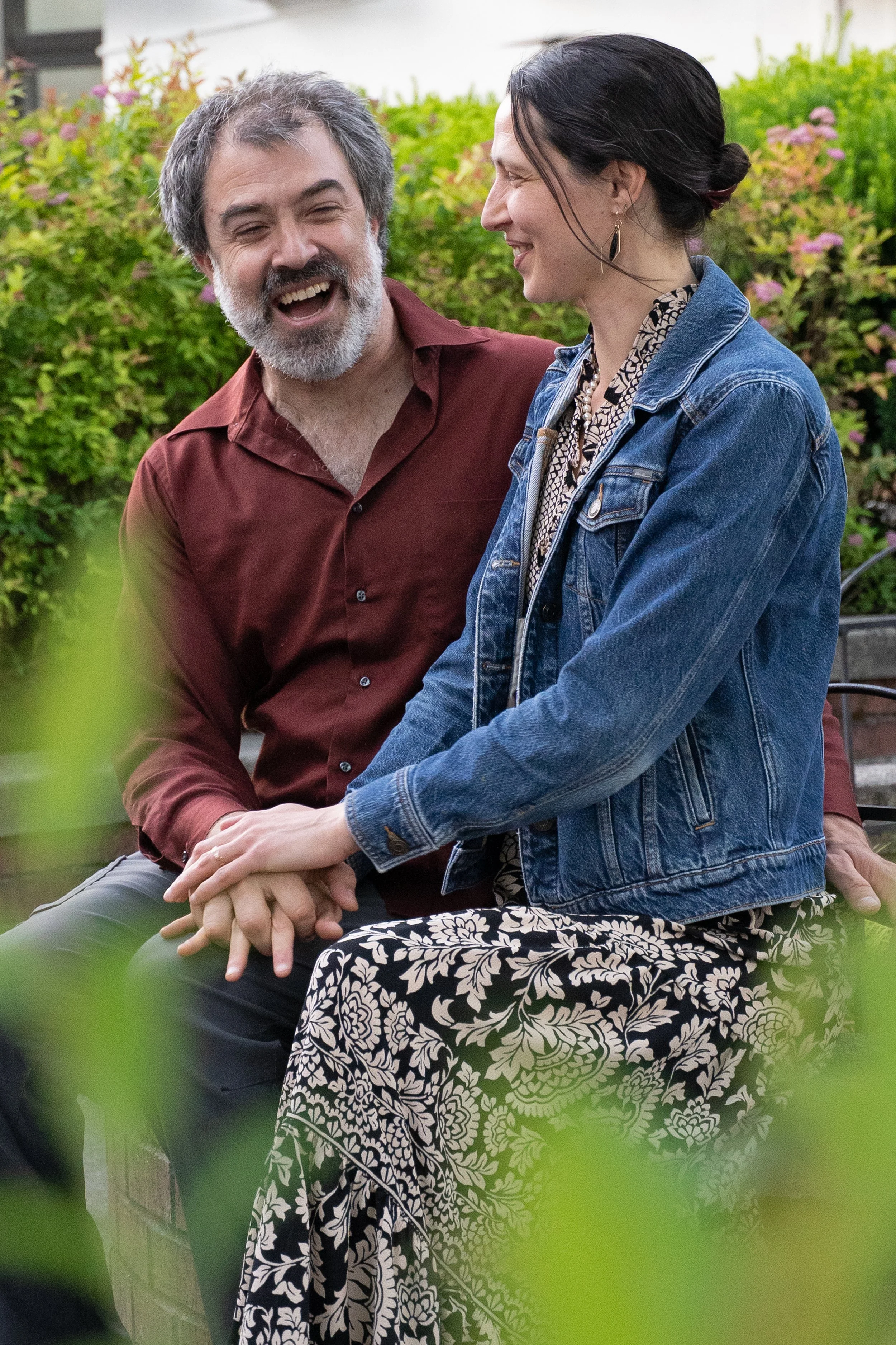 Eric Fair-Layman (left) and Erin Boyt (right) laughing with each other outdoors on a late spring evening.