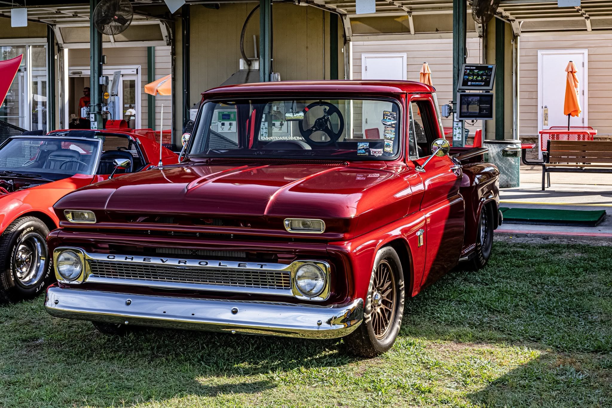 Spotted this absolute stunner at the show. You just can't beat a classic red Chevy truck basking in the outdoor sun. Even with a modern sports car creeping into the frame and the bustling event venue behind it, this vintage beauty stole the whole dam