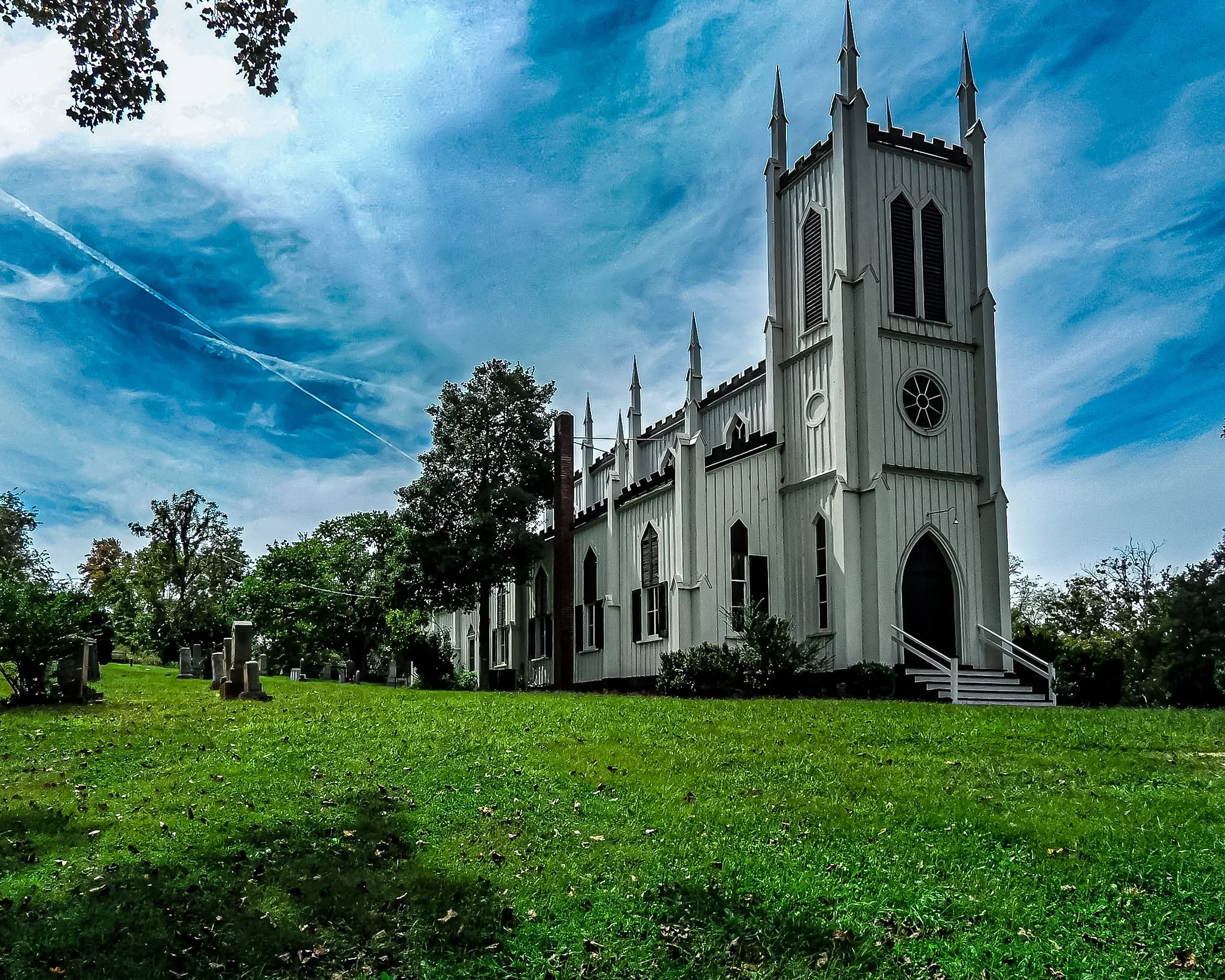 I stumbled upon this breathtaking white church, its sharp Gothic spires cutting sharply against a canvas of drifting clouds. There’s a beautiful contrast between the crisp, white structure and the vibrant green grass stretching out around it. The cir