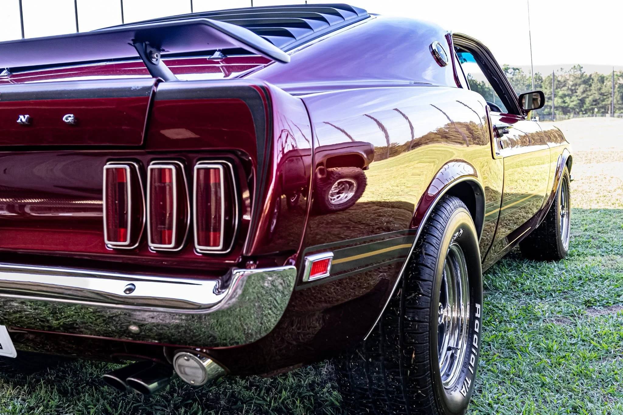 My absolute dream: the rear view of a classic red MUSTANG parked, showing off its flawless glossy paint, roaring dual exhaust, and those iconic, distinctive taillights.