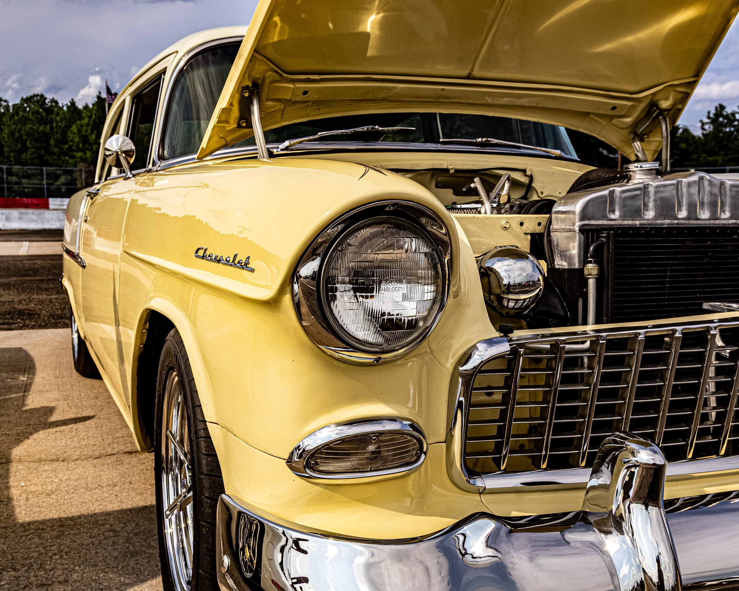 There’s nothing quite like the sight of a classic. This vintage yellow Chevy is sitting out with her hood propped open, giving a little peak at the engine underneath. I was standing here looking at that iconic Chevrolet emblem, the polished chrome bu