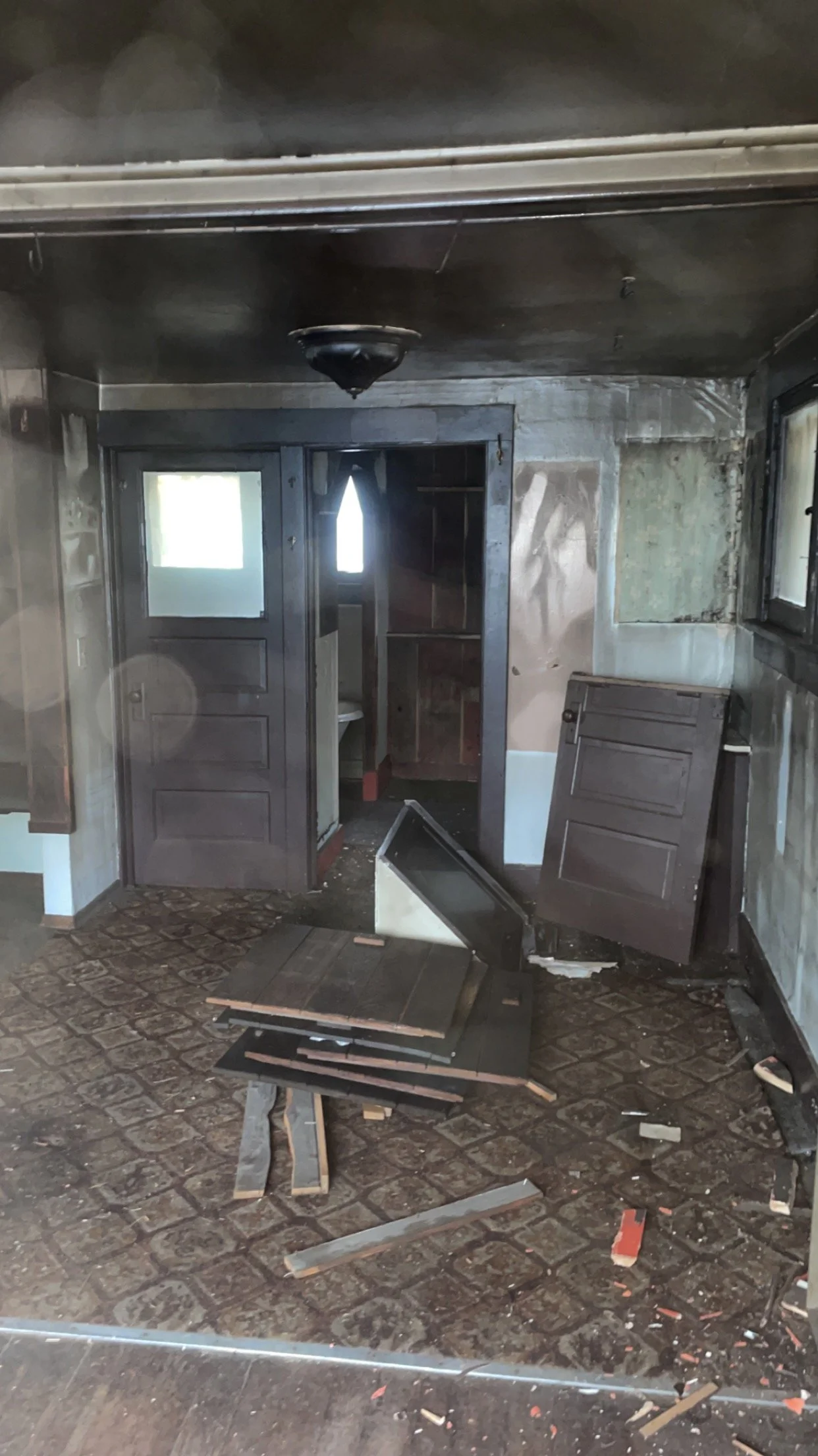 Abandoned room with debris, broken doors, and damaged flooring.