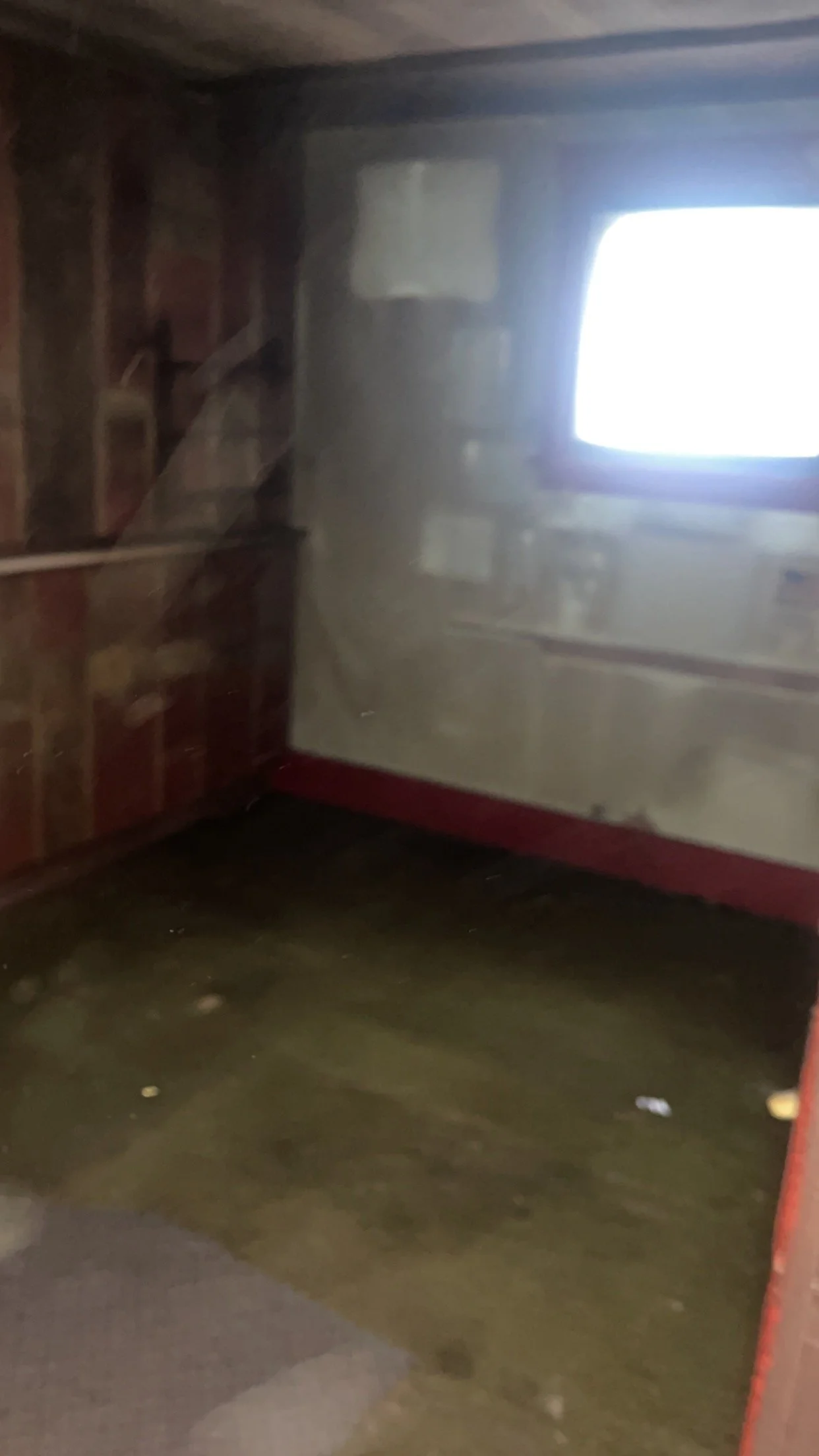 Empty, dimly lit room with a small window and bare walls.