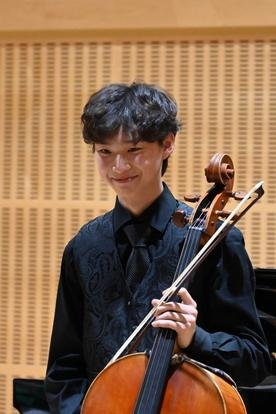 Young man holding a cello and bow in a music studio