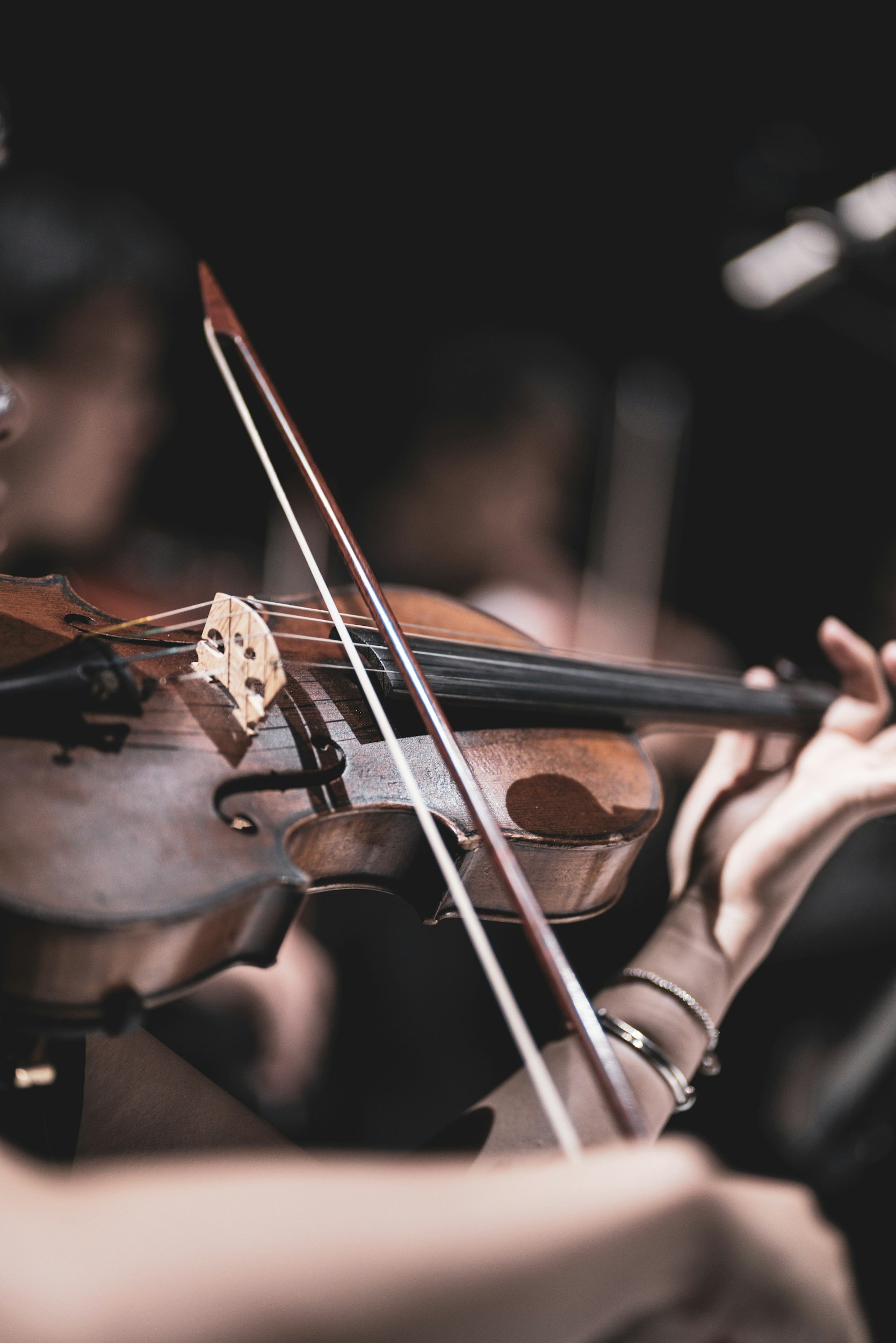 Person playing the violin, with focus on the violin and bow, and blurred background.