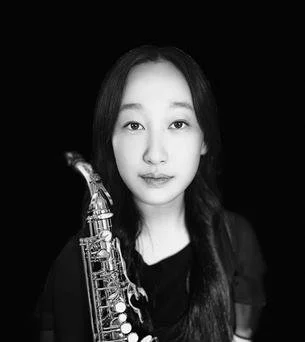 Black and white portrait of a woman with long hair holding a saxophone.