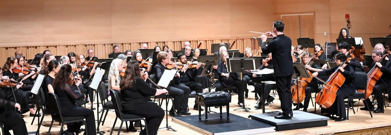 Orchestra performing on stage with conductor leading.
