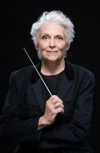 Conductor holding a baton with a confident expression