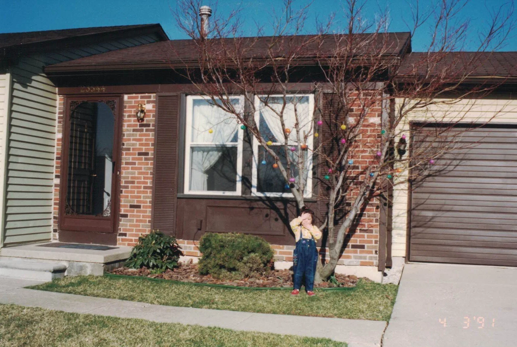 Dr. Cassie Lopez-Jeng as a toddler standing in front of a small house.
