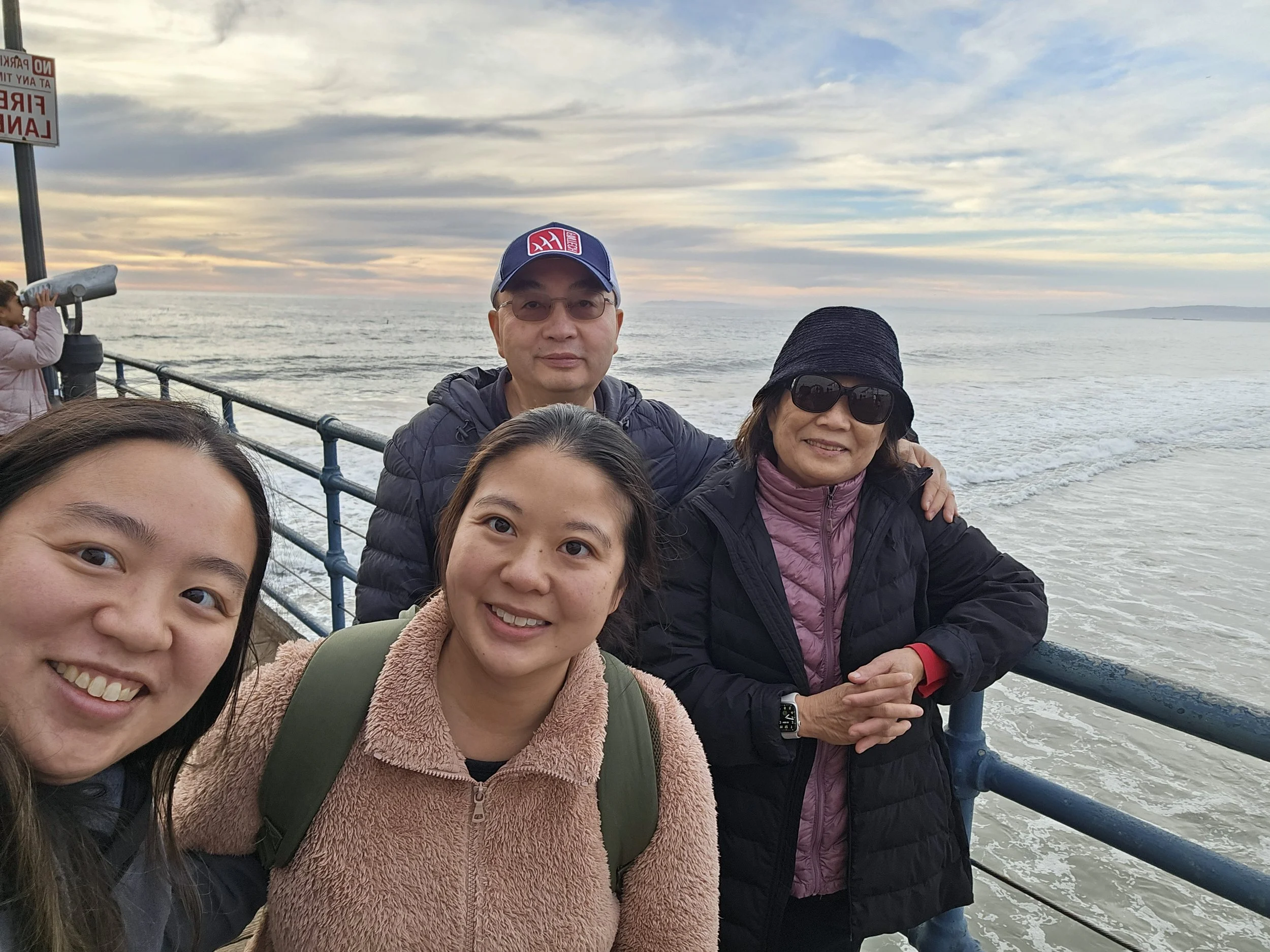 Dr. Cassie Lopez-Jeng with her parents and her sister on an ocean pier.