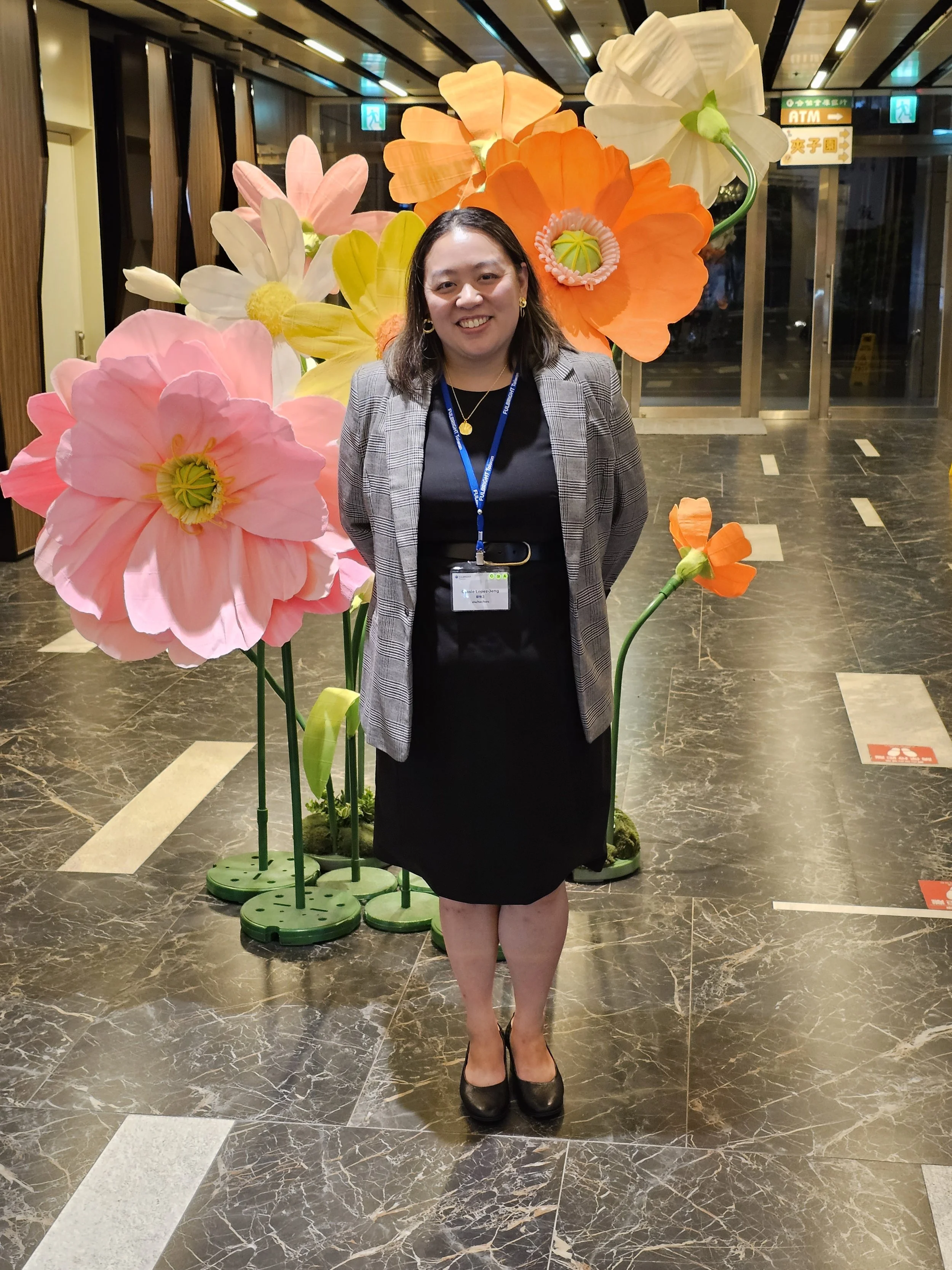 Dr. Cassie Lopez-Jeng standing in front of a flower sculpture.