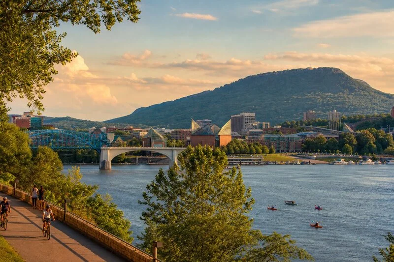 Scenic Chattanooga, Tennessee, waterfront with the Tennessee River, bridges, kayaks, downtown buildings, and Lookout Mountain at sunset